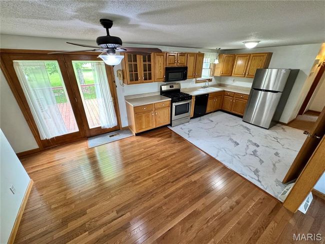 Kitchen featuring black appliances, a sink, light wood finished floors, light countertops, and a textured ceiling | Image 20