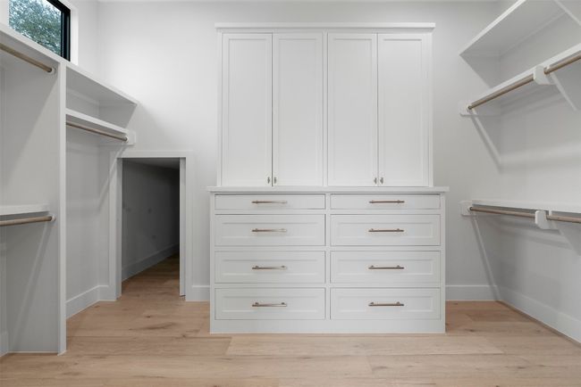 A spacious walk-in closet provides ample storage, thoughtfully designed for both fashion and function, with custom-built shelving and drawers | Image 20