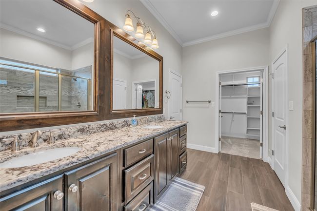 Full bathroom featuring a spacious closet, a stall shower, double vanity, ornamental molding, and healthy amount of natural light | Image 21