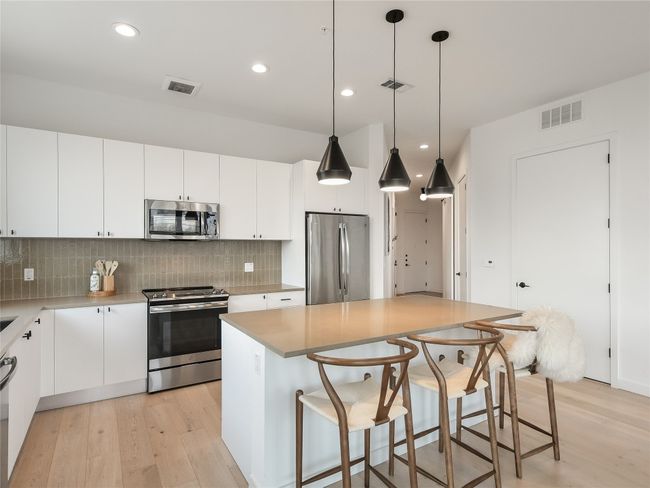Kitchen with tasteful backsplash, visible vents, appliances with stainless steel finishes, and light wood-style floors | Image 10