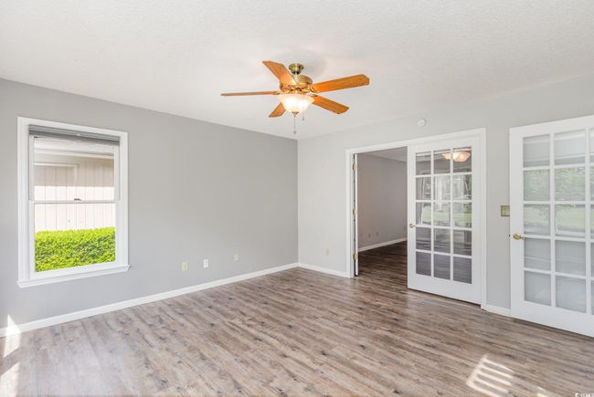 Unfurnished room featuring baseboards, wood finished floors, a wealth of natural light, and ceiling fan | Image 22