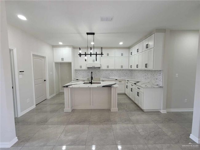Kitchen with white cabinetry, sink, pendant lighting, and a center island with sink | Image 9