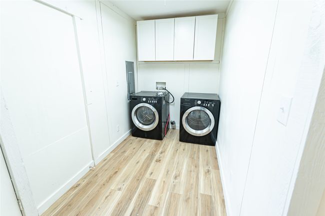 Washroom featuring electric panel, cabinet space, light wood-style floors, and independent washer and dryer | Image 7