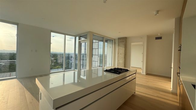 Kitchen featuring stainless steel gas cooktop, light wood-type flooring, expansive windows, baseboards, and white cabinetry | Image 13
