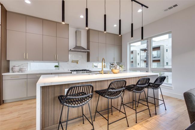 Kitchen with sink, gray cabinetry, wall chimney range hood, a kitchen island with sink, and backsplash | Image 14