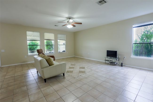 Living room with light tile patterned floors, visible vents, baseboards, and a ceiling fan | Image 5