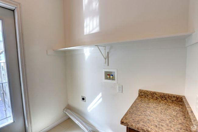 Washroom featuring electric dryer hookup, light tile patterned floors, laundry area, and washer hookup | Image 26
