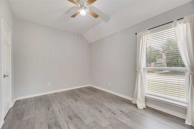 Spare room featuring wood finished floors, baseboards, a ceiling fan, and vaulted ceiling | Image 9