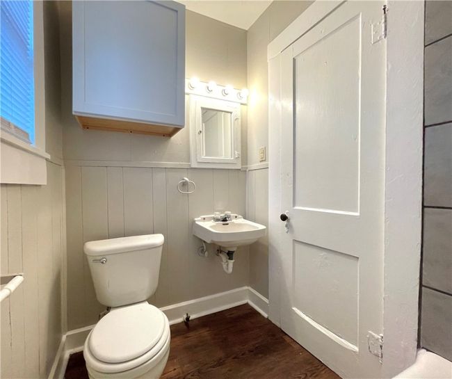Half bathroom with toilet, a wainscoted wall, wood finished floors, and a sink | Image 9
