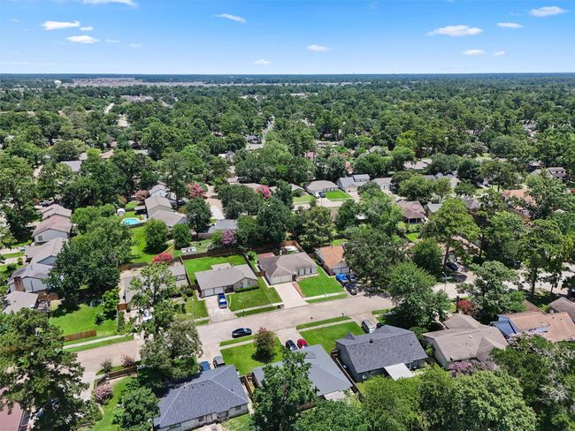 This aerial photo showcases a lush, tree-lined suburban neighborhood with well-maintained homes and spacious yards. The area appears peaceful and inviting, ideal for families seeking a tranquil living environment. | Image 30