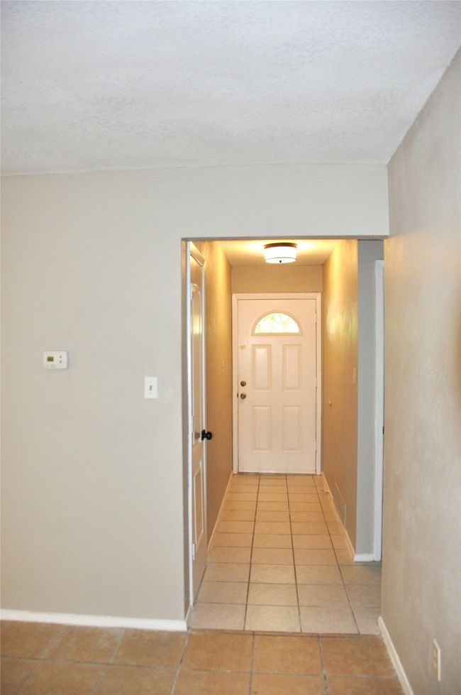 Looking back out to the front door from the living room with baseboards and light tile patterned flooring | Image 5