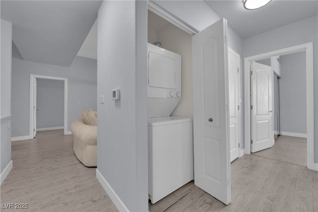 Laundry room with stacked washer and clothes dryer and light wood finished floors | Image 35