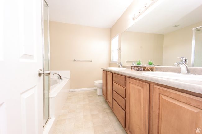 Bathroom attached to the primary suite, featuring a garden tub, a sink, a double vanity, and a toilet. | Image 19