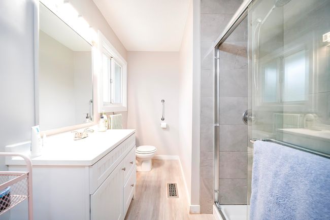 Full bath with toilet, vanity, a shower stall, wood finished floors, and visible vents | Image 16
