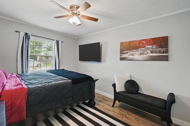 Bedroom with ornamental molding, wood finished floors, and a ceiling fan | Image 22