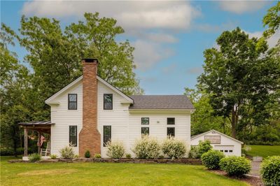 Rear view of house with a garage, a yard, and an outdoor structure | Image 1