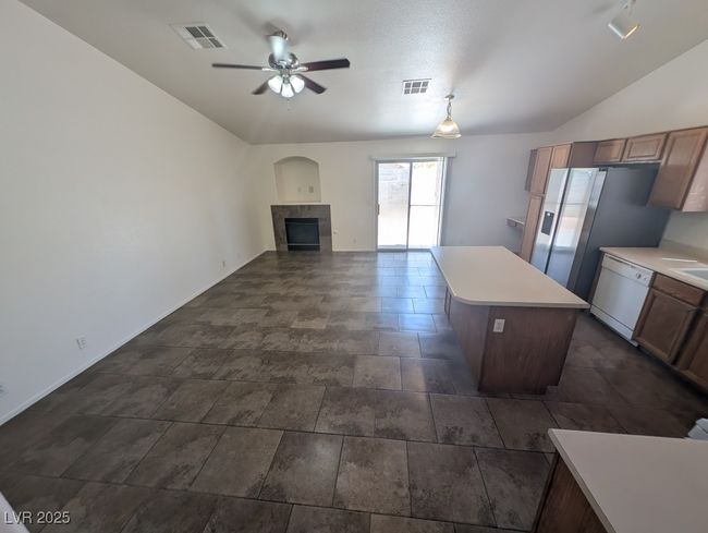 Kitchen with a tiled fireplace, visible vents, a ceiling fan, and white dishwasher | Image 7
