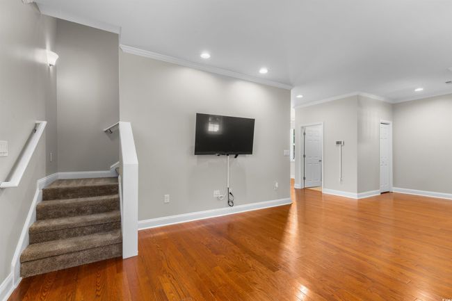 Unfurnished living room featuring wood finished floors, ornamental molding, stairs, recessed lighting, and baseboards | Image 6