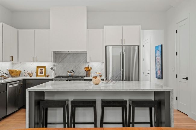 Kitchen featuring appliances with stainless steel finishes, a kitchen breakfast bar, tasteful backsplash, and light stone countertops | Image 14