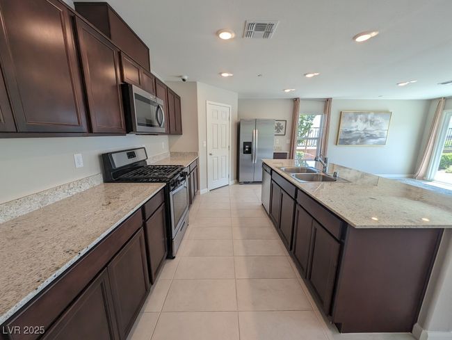 Kitchen featuring stainless steel appliances, healthy amount of natural light, a kitchen island with sink, dark brown cabinetry, and recessed lighting | Image 9