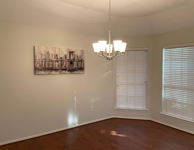 Empty room featuring dark wood-style floors and a chandelier | Image 11