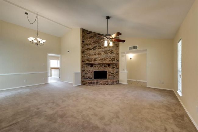 Unfurnished living room with a ceiling fan, a brick fireplace, carpet flooring, high vaulted ceiling, and baseboards | Image 4