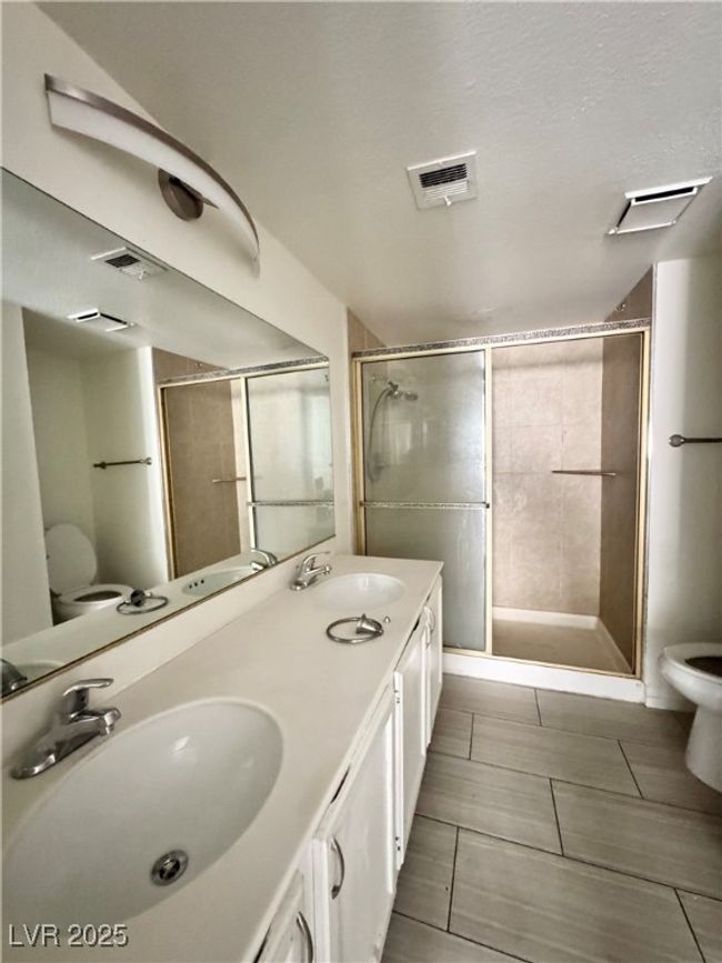 Full bath featuring toilet, a stall shower, double vanity, and tile patterned floors | Image 12