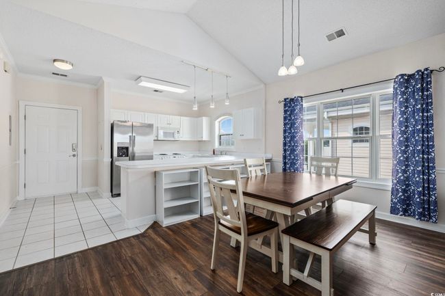 Dining area with light wood finished floors, rail lighting, baseboards, lofted ceiling, and ornamental molding | Image 8