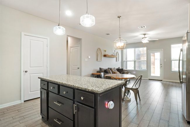 Kitchen featuring freestanding refrigerator, light wood-style floors, baseboards, open floor plan, and decorative light fixtures | Image 8
