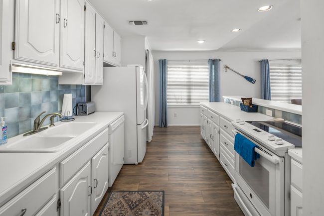 Kitchen with a sink, decorative backsplash, white appliances, and white cabinetry | Image 5