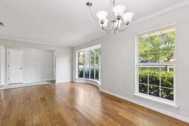 Empty room with hardwood / wood-style flooring, a chandelier, crown molding, and healthy amount of natural light | Image 12