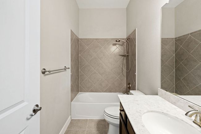 Full bath with toilet, tile patterned flooring, vanity, and shower combination | Image 34