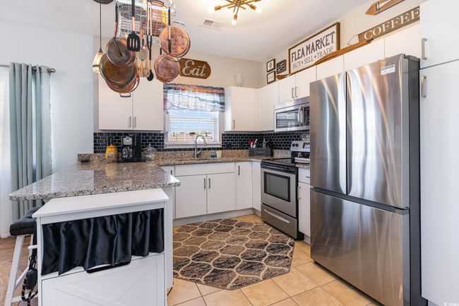 Kitchen featuring a sink, stainless steel appliances, tasteful backsplash, and white cabinets | Image 8