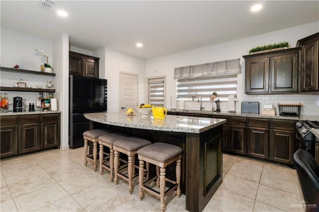 Kitchen with visible vents, a kitchen island, a breakfast bar area, freestanding refrigerator, and backsplash | Image 8