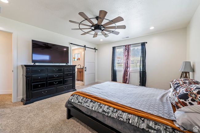 Bedroom with light carpet, a barn door, baseboards, visible vents, and recessed lighting | Image 20