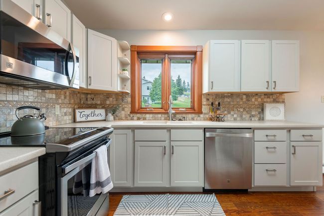 Kitchen with appliances with stainless steel finishes, light countertops, recessed lighting, dark wood-style floors, and white cabinets | Image 7