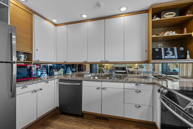 Kitchen featuring a sink, open shelves, appliances with stainless steel finishes, dark wood-style floors, and white cabinets | Image 17