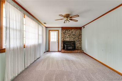 Unfurnished living room with ceiling fan, ornamental molding, light carpet, and a fireplace | Image 3