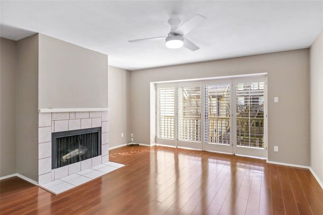 Unfurnished living room featuring a fireplace, ceiling fan, wood finished floors, and baseboards | Image 6