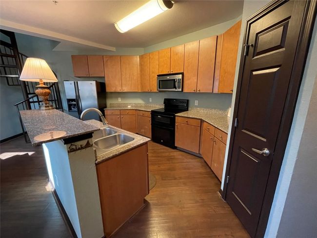 Kitchen with stainless steel appliances, a sink, dark wood finished floors, and an island with sink | Image 5