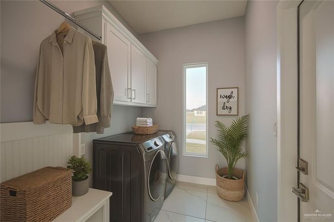 Laundry area with washing machine and dryer, cabinet space, healthy amount of natural light, and light tile patterned floors | Image 26