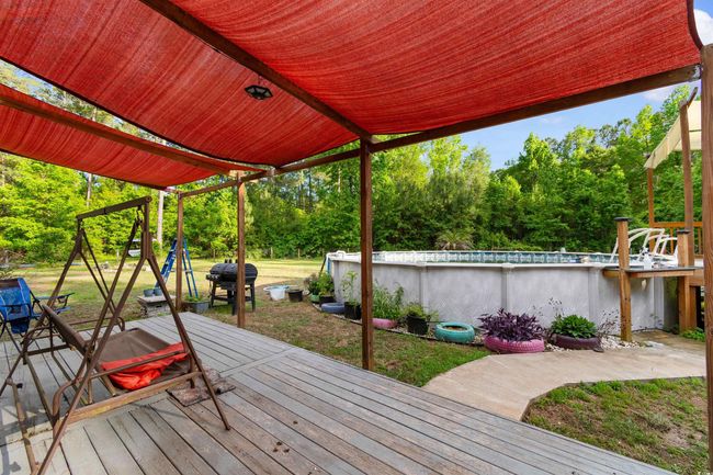 Wooden deck featuring an outdoor pool, area for grilling, a yard, and view of wooded area | Image 27