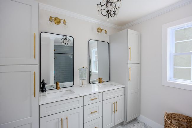 Full bathroom with a chandelier, double vanity, crown molding, and a tile shower | Image 27