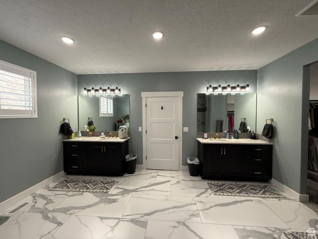 Bathroom with a textured ceiling, visible vents, baseboards, recessed lighting, and two vanities | Image 39