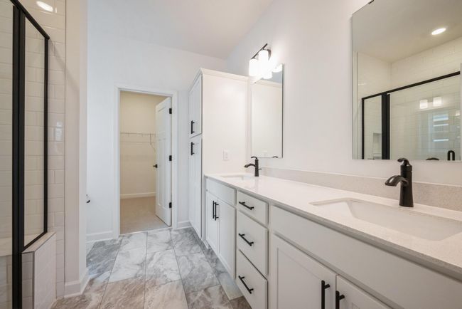 Photo of actual home. The primary ensuite bathroom offers a large double vanity, separate shower, a leads into the large walk-in closet | Image 7
