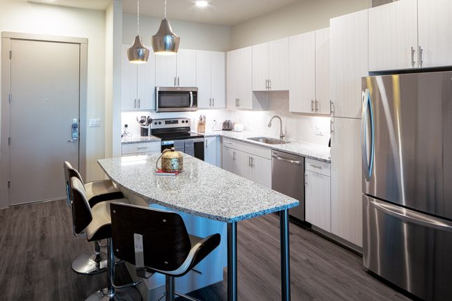 Kitchen featuring pendant lighting, white cabinets, sink, dark wood-type flooring, and appliances with stainless steel finishes | Image 4