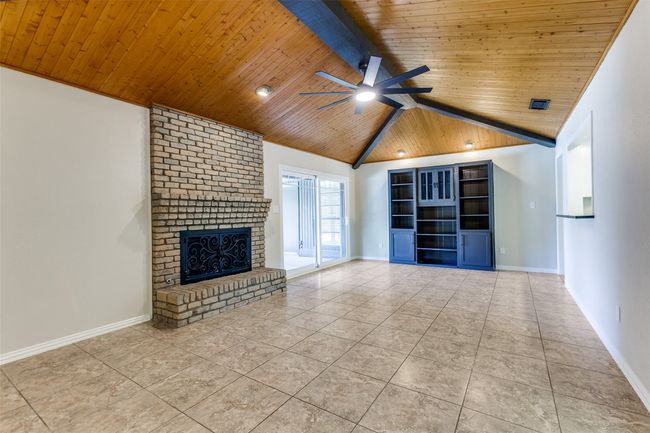 Unfurnished living room with wood ceiling, a ceiling fan, a brick fireplace, and tile patterned flooring | Image 8
