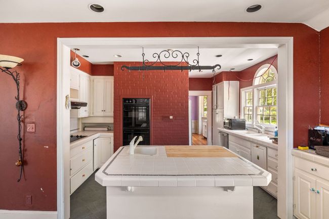 Kitchen with black appliances, tile counters, a kitchen island, white cabinetry, and recessed lighting | Image 13
