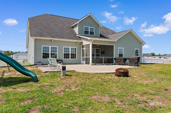 Back of house featuring a fire pit, a sunroom, a patio, a playground, and roof with shingles | Image 35