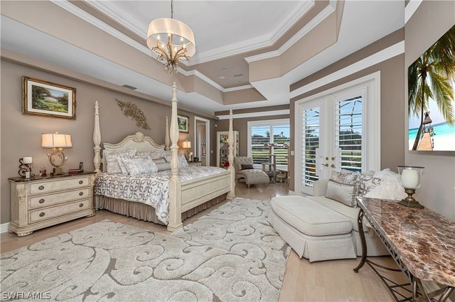 Oversized Primary Bedroom Suite with crown moulding, raised ceilings, wood floors and French doors leading to pool area. Adjacent to massive walk-in closet and pool bath | Image 22